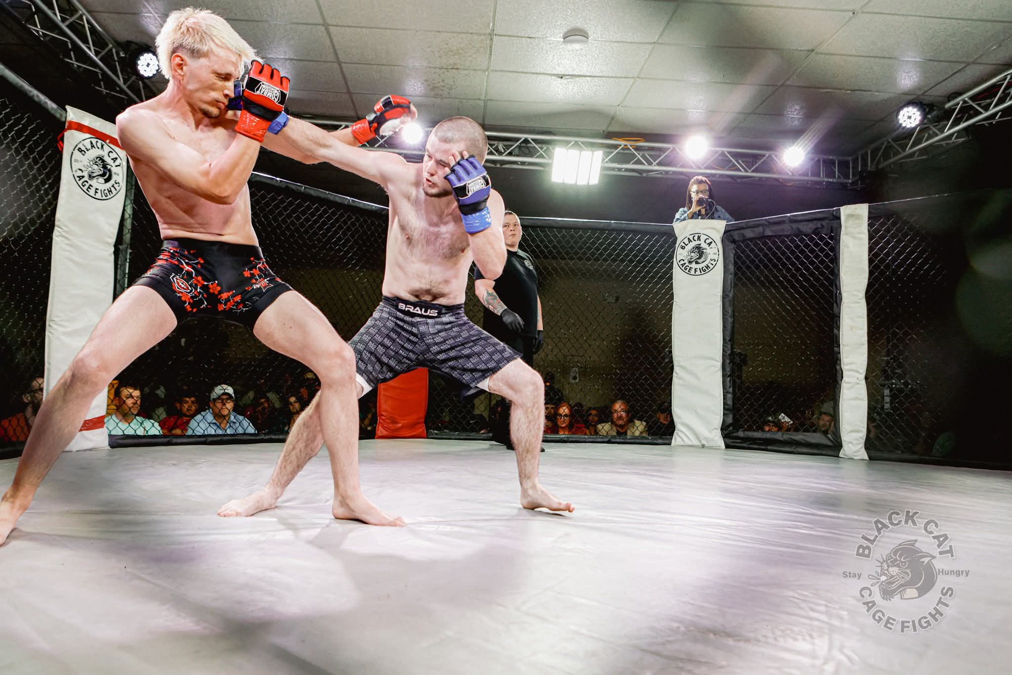 Two mixed martial arts fighters trading strikes inside the Black Cat cage